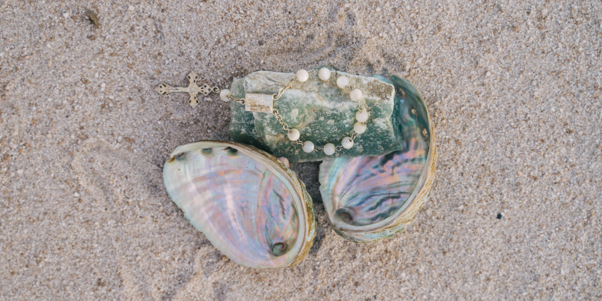 several shells are laying on the sand including one that has a cross on it