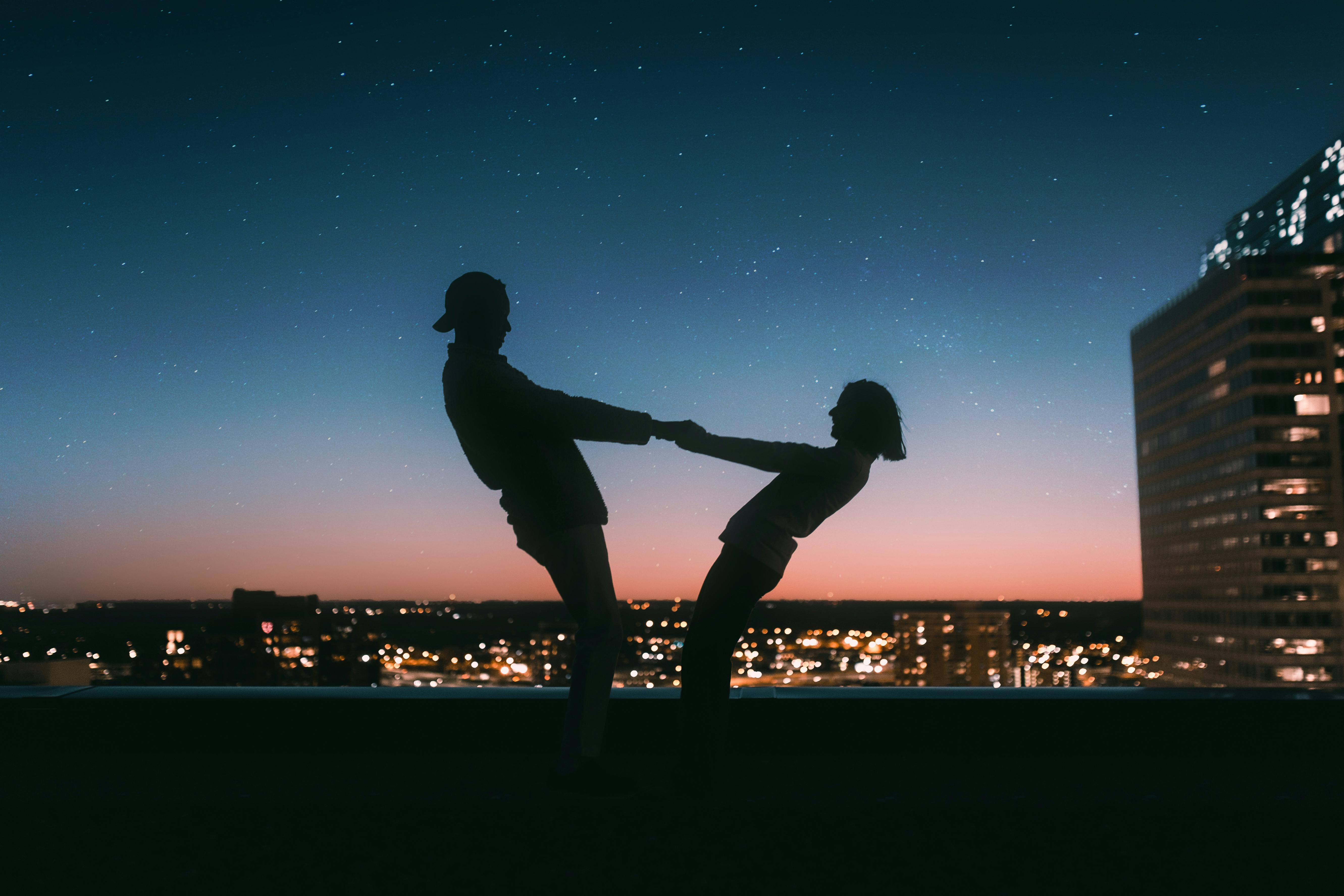 a man and a woman are dancing on a rooftop at night .