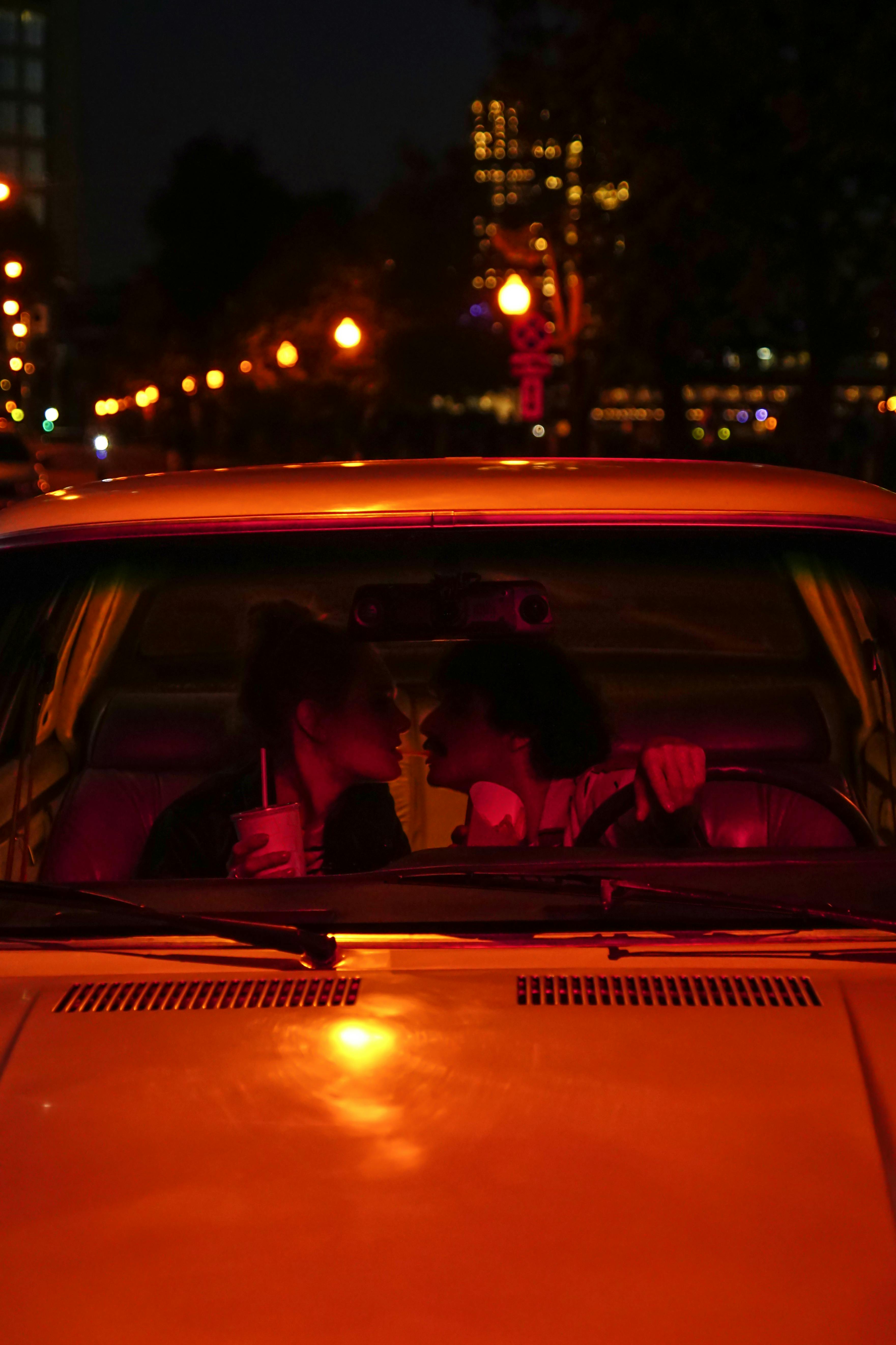 a man and a woman are kissing in a car at night .