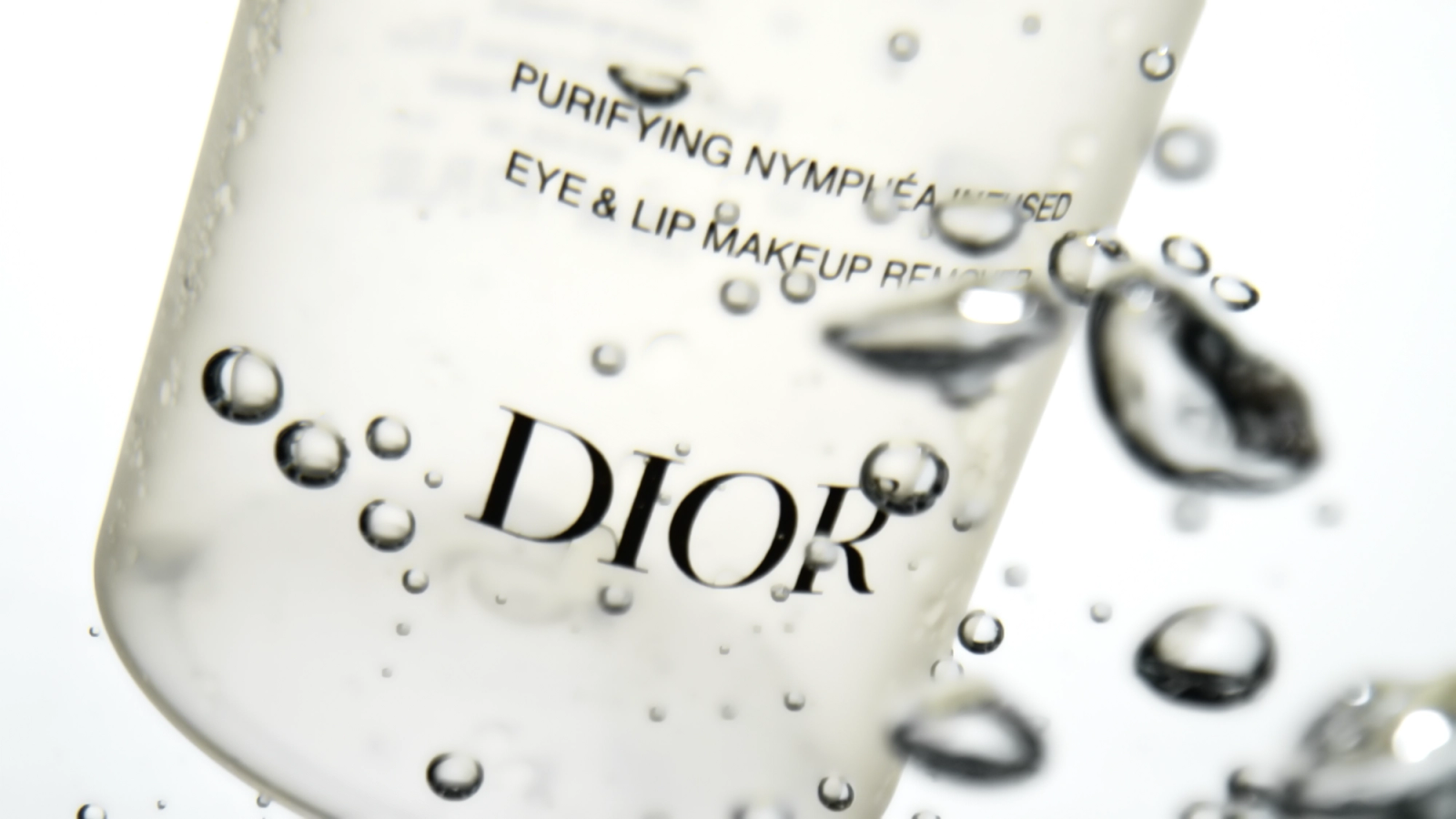 Close-up still from a personal video project of a Dior Purifying Nymphéa Infused Eye & Lip Makeup Remover bottle covered in water droplets and bubbles