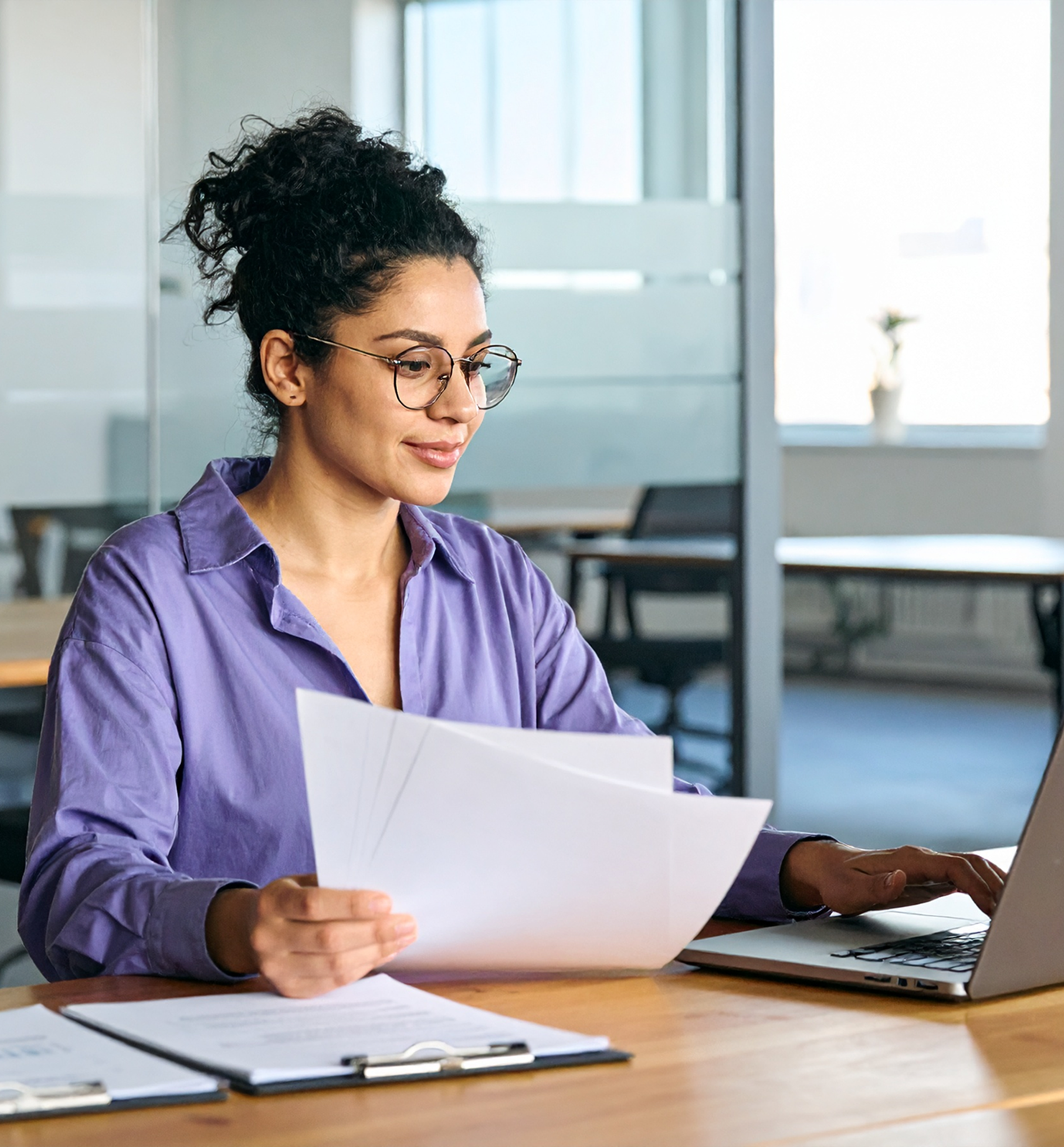 Woman works at a desk with papers and a laptop