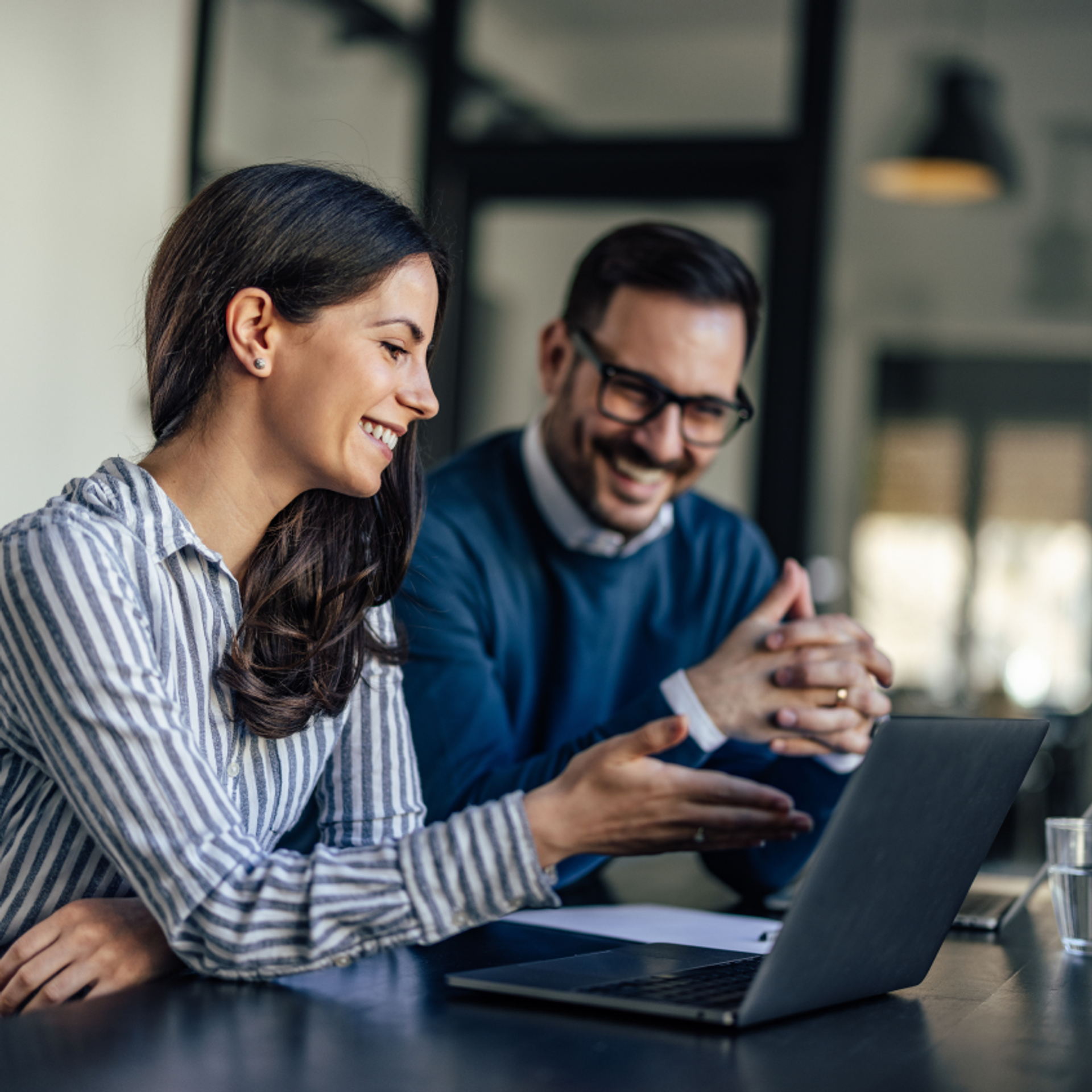 A woman and a man talking while working on a computer