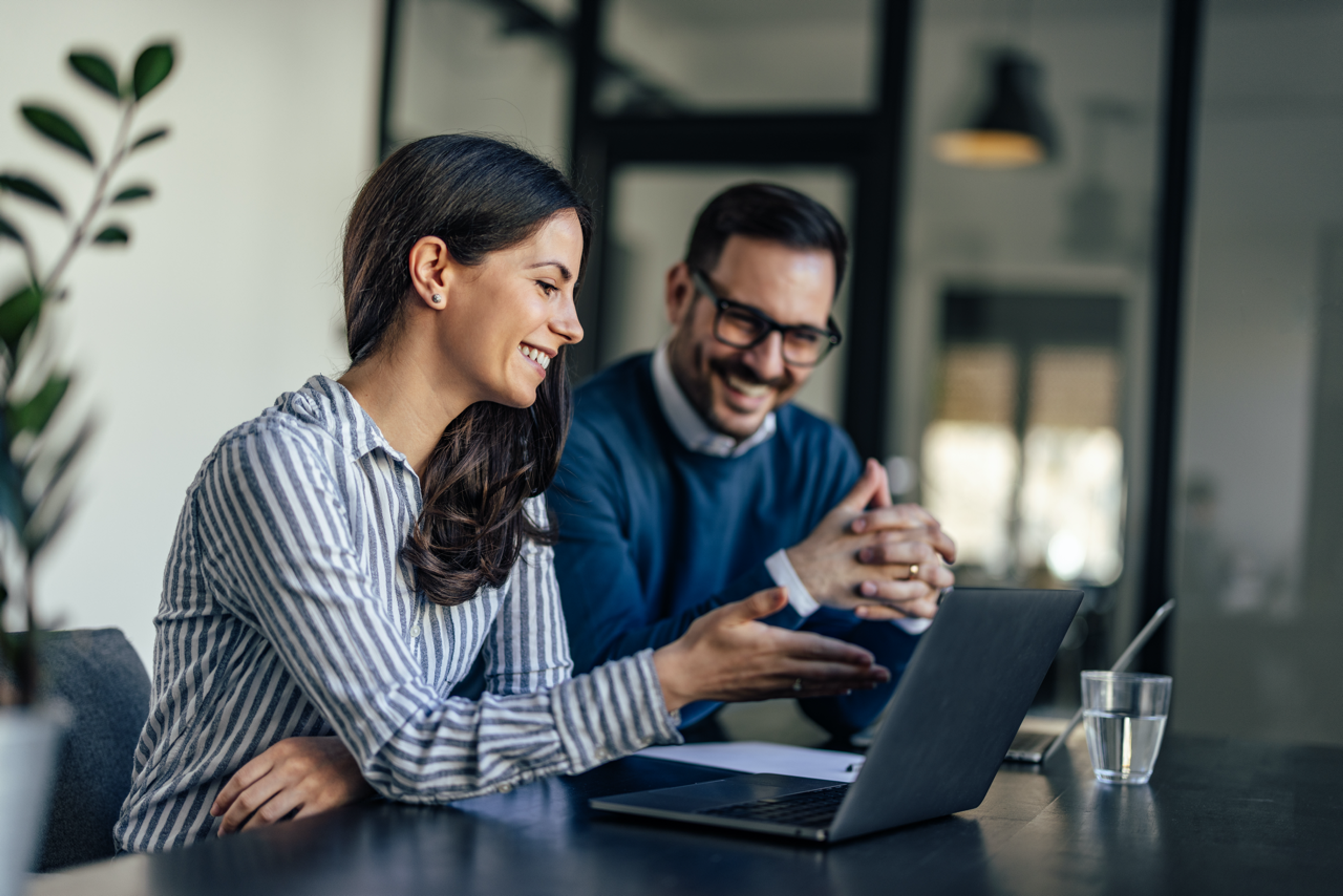 A woman and a man talking while working on a computer