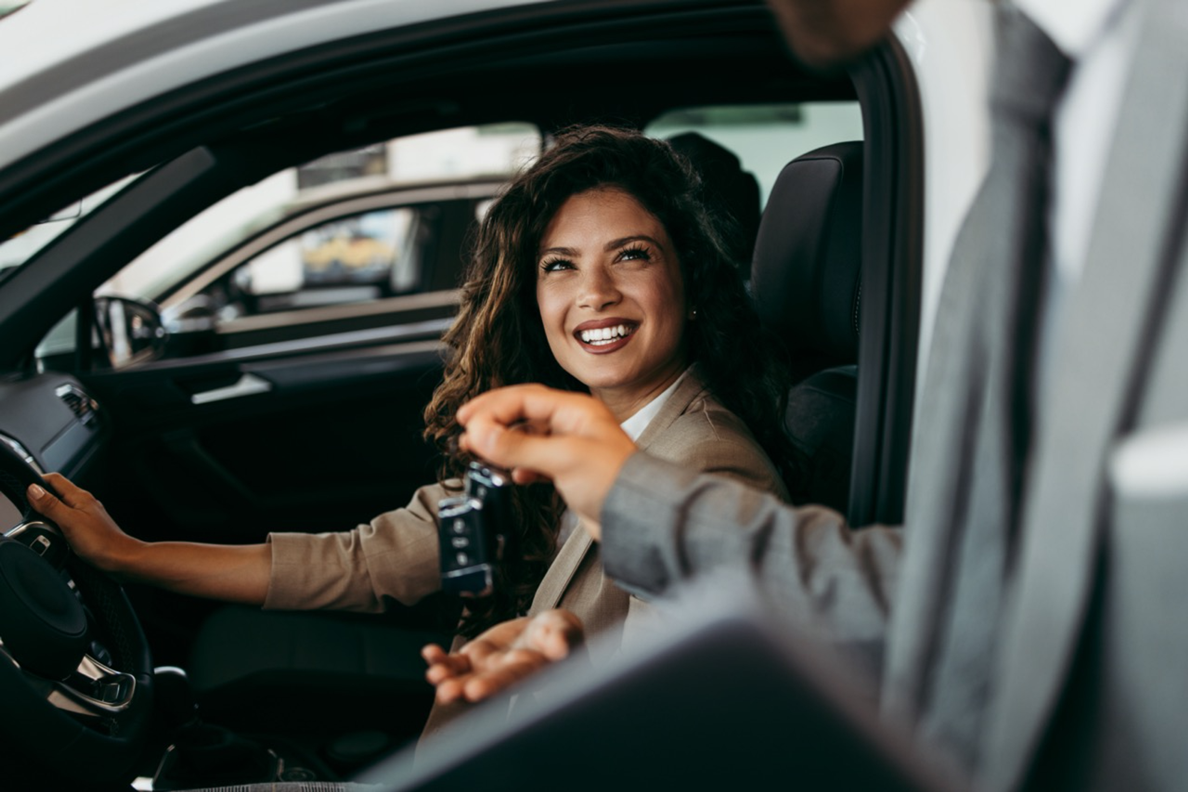 Woman in a car receiving car keys from salesperson