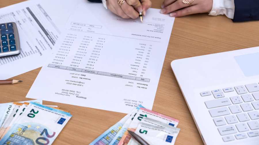 A person going through invoices and euro bills on the desk