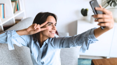 Generation Z girl taking a selfie showing peace sign with her hand