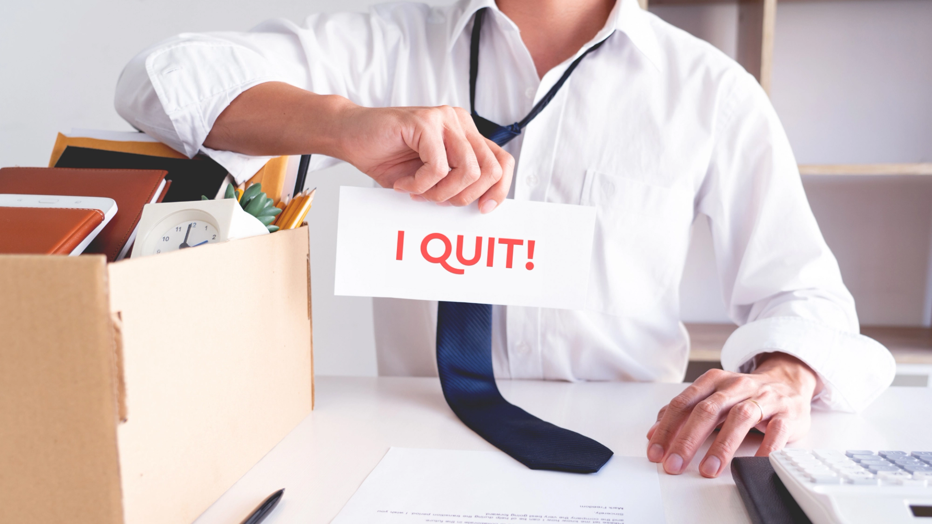 Employee holding a paper with "I quit" written on it.