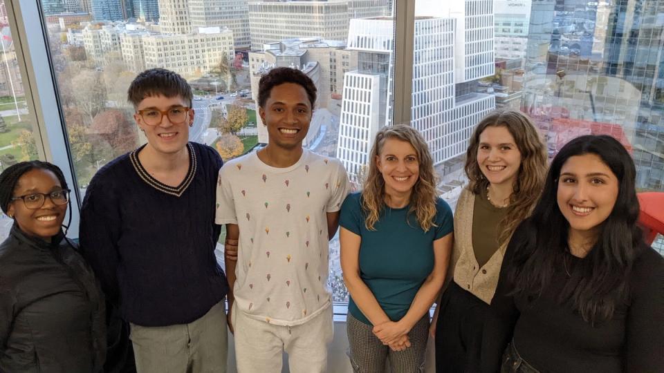 Six members of the research team stand together in front of a window overlooking the city.
