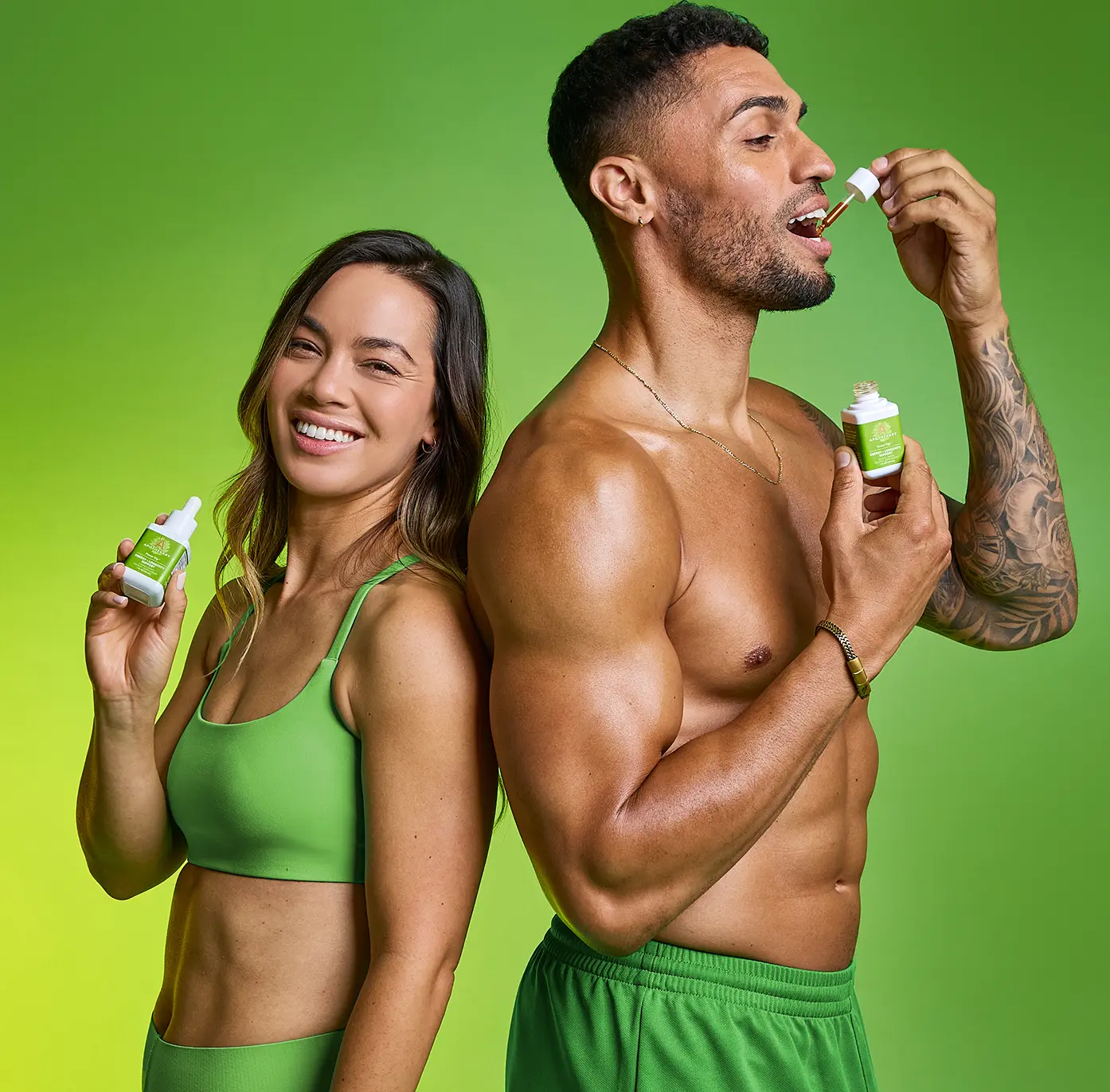 A smiling woman and a man standing back-to-back, each holding a bottle of Apothékary Power Trip™, with the man taking the tincture directly from the dropper.