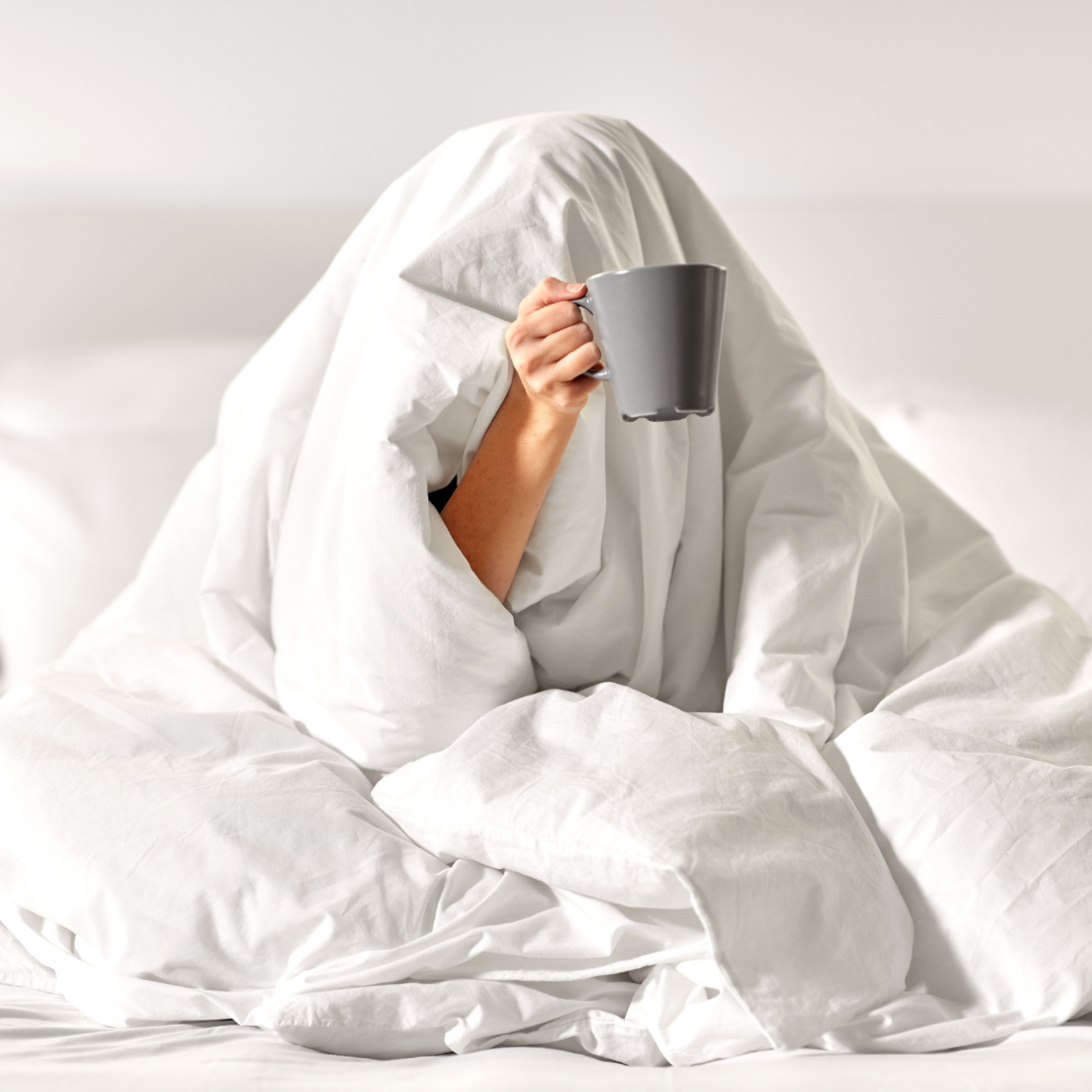 girl sleeping under comforters with mug