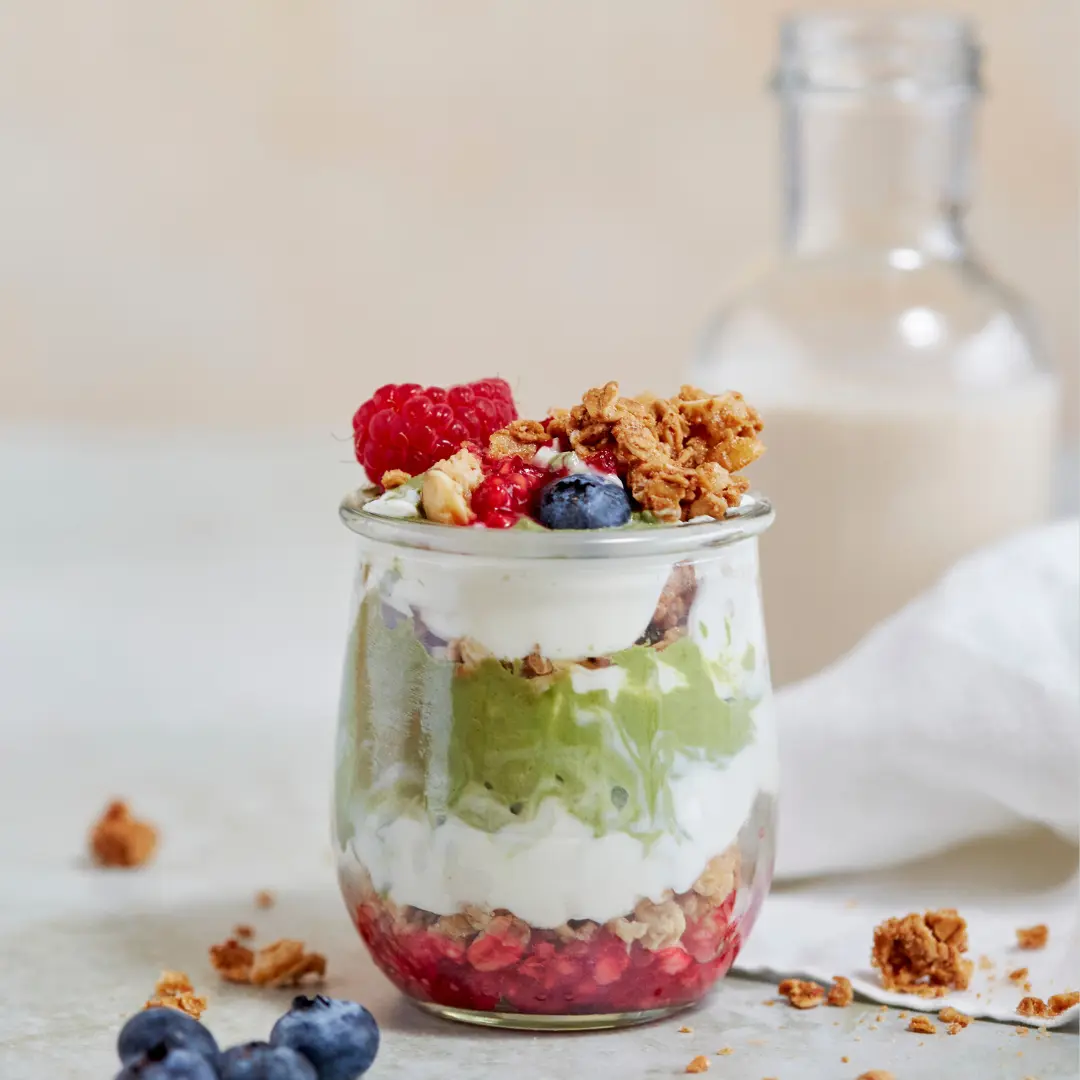 small parfait in a class jar with fruit and granola on top