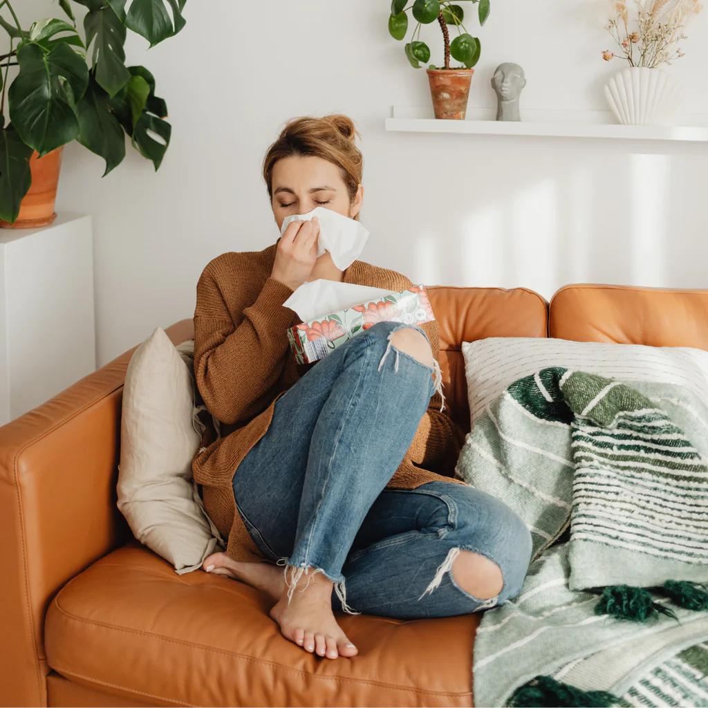 woman sitting on a sofa with a box of tissues