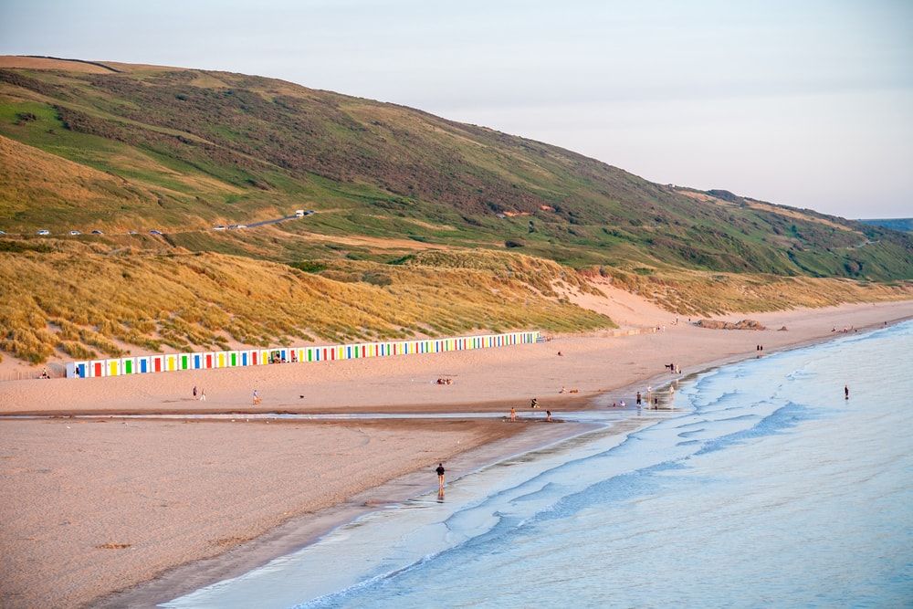 The shores and colourful beach huts of Woolacombe Beach in Devon, one of the UK's best beaches