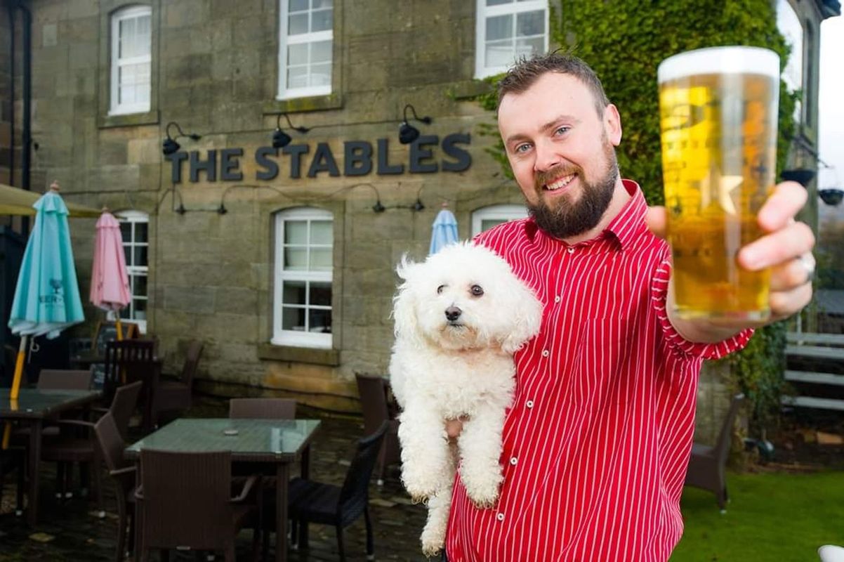 A man and his dog pose for the camera outside The Stables, a dog-friendly pub in Scotland