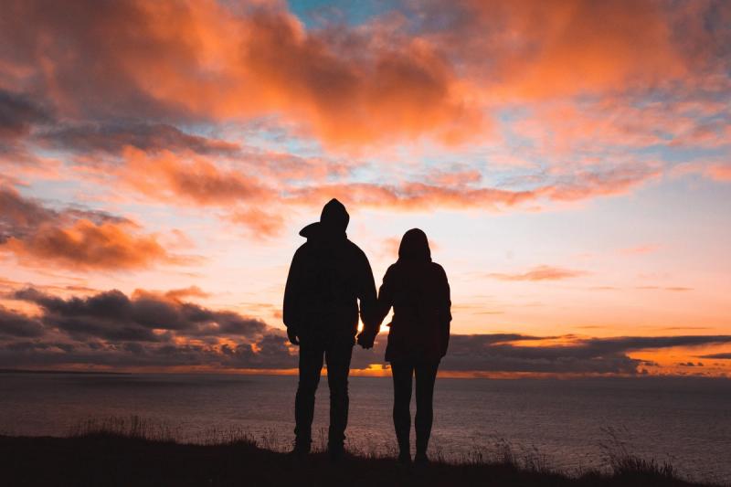 A couple hold hands as the sun sets, enjoying a romantic holiday with Last Minute Cottages