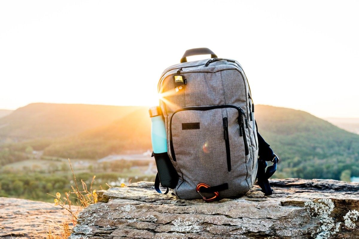 A backpack rests on a rock during a scenic sunset, a compact and responsible way to travel