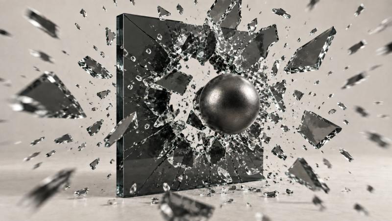 A gunmetal cannonball bursts through a dark glass panel, sending large shards and small fragments flying in every direction.