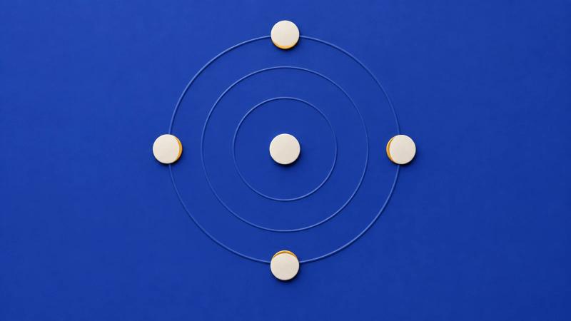 Concentric ripples from a central ivory disc reach four evenly spaced discs on a matte blue surface.