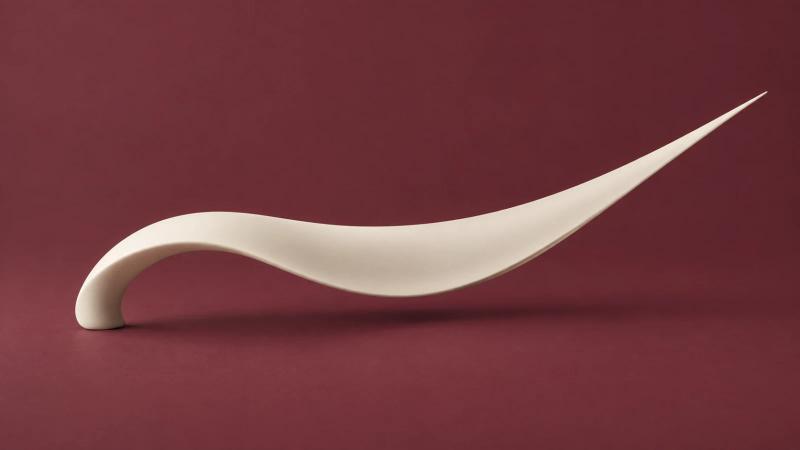 A flowing ivory wing-like sculpture curves upward against a deep wine-red background.