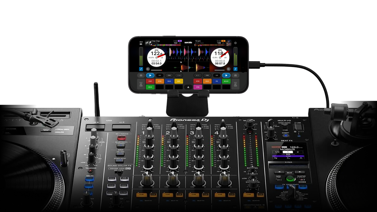 An iPhone running Serato DJ for iOS on a stand, connected to a DJ mixer and turntables for DVS