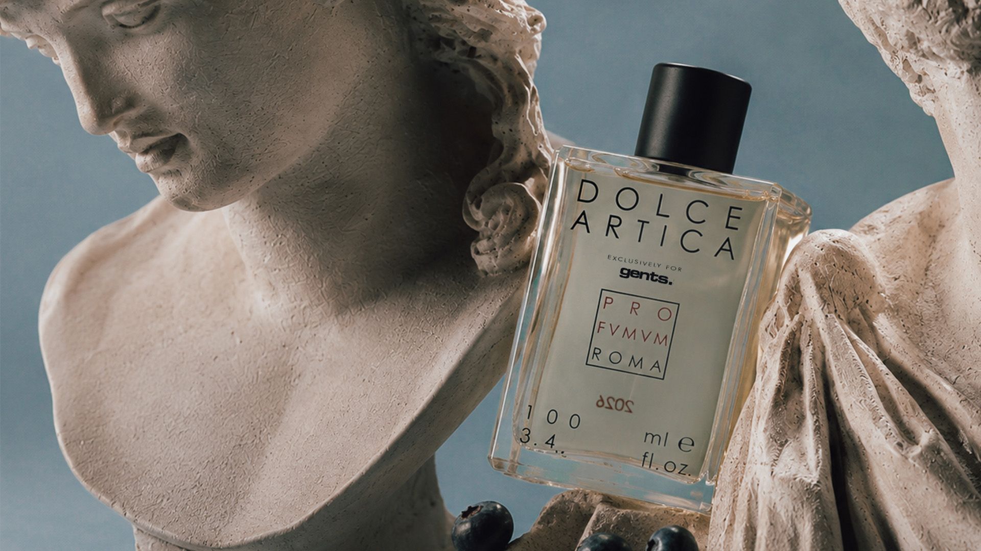 A Dolce Artica perfume bottle beside a classical marble statue.