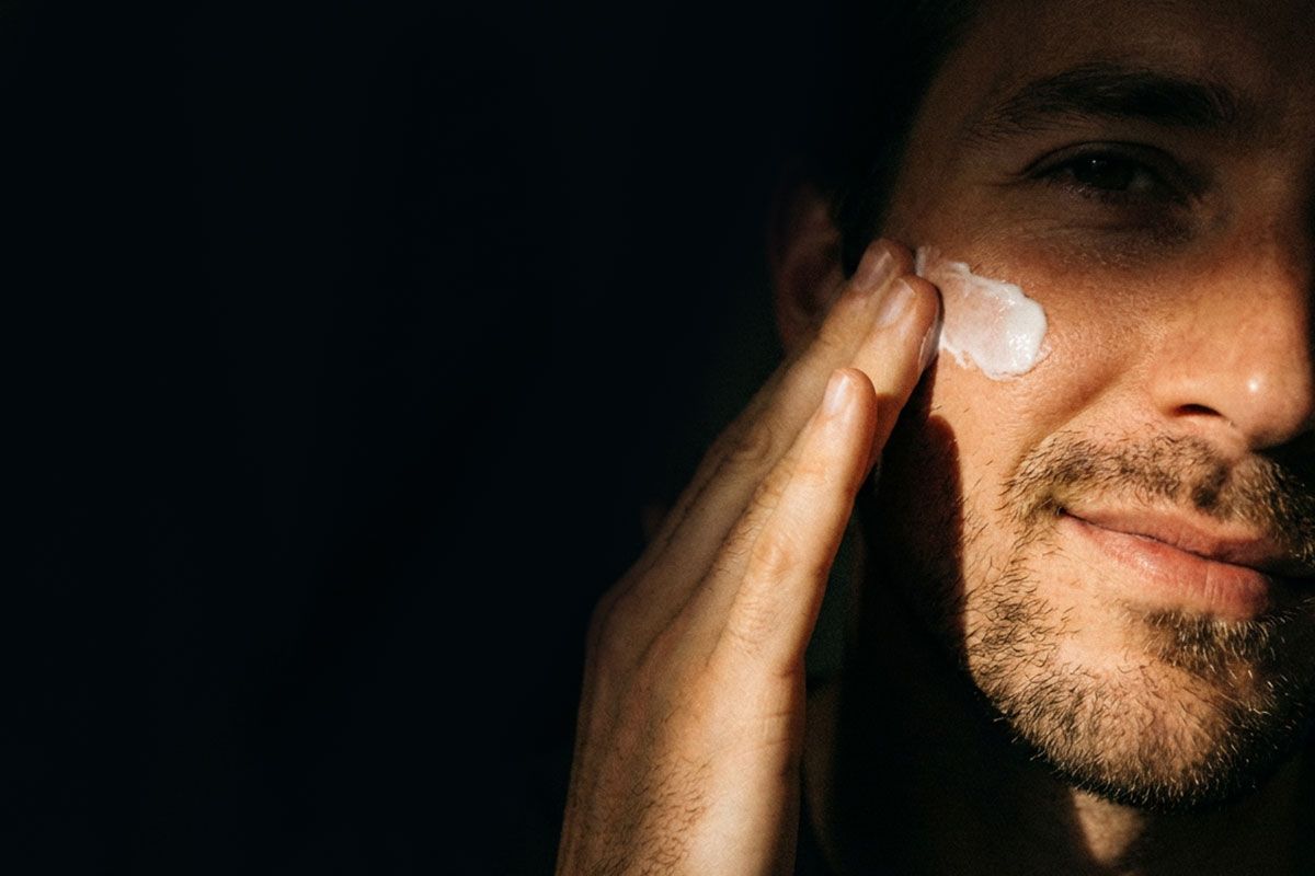 Mies, joka levittää kasvovoidetta poskelleen