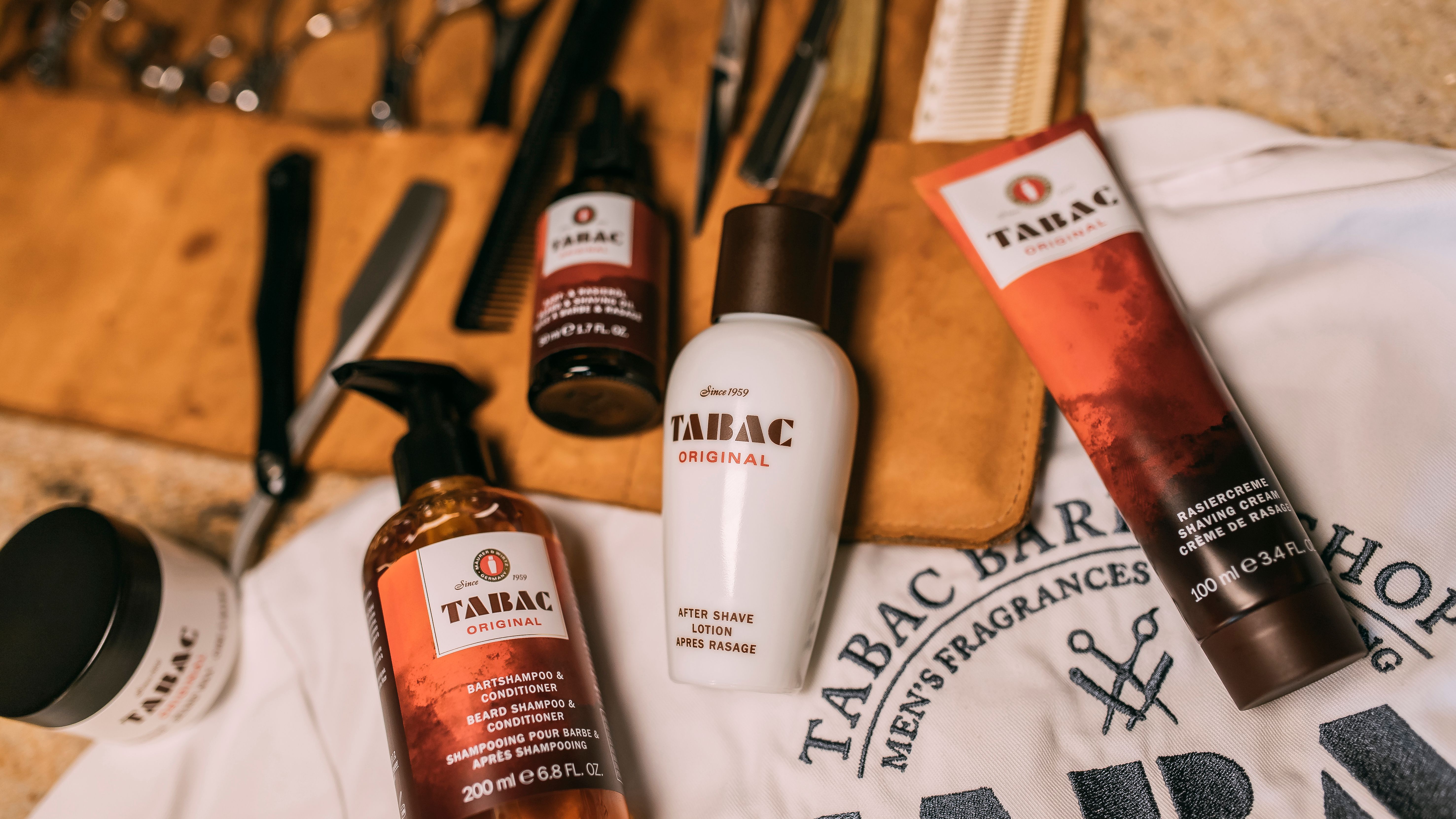 Tabac Original -parranajo- ja parranhoitotuotteita sekä parturivälineitä brändätyn T-paidan päällä.