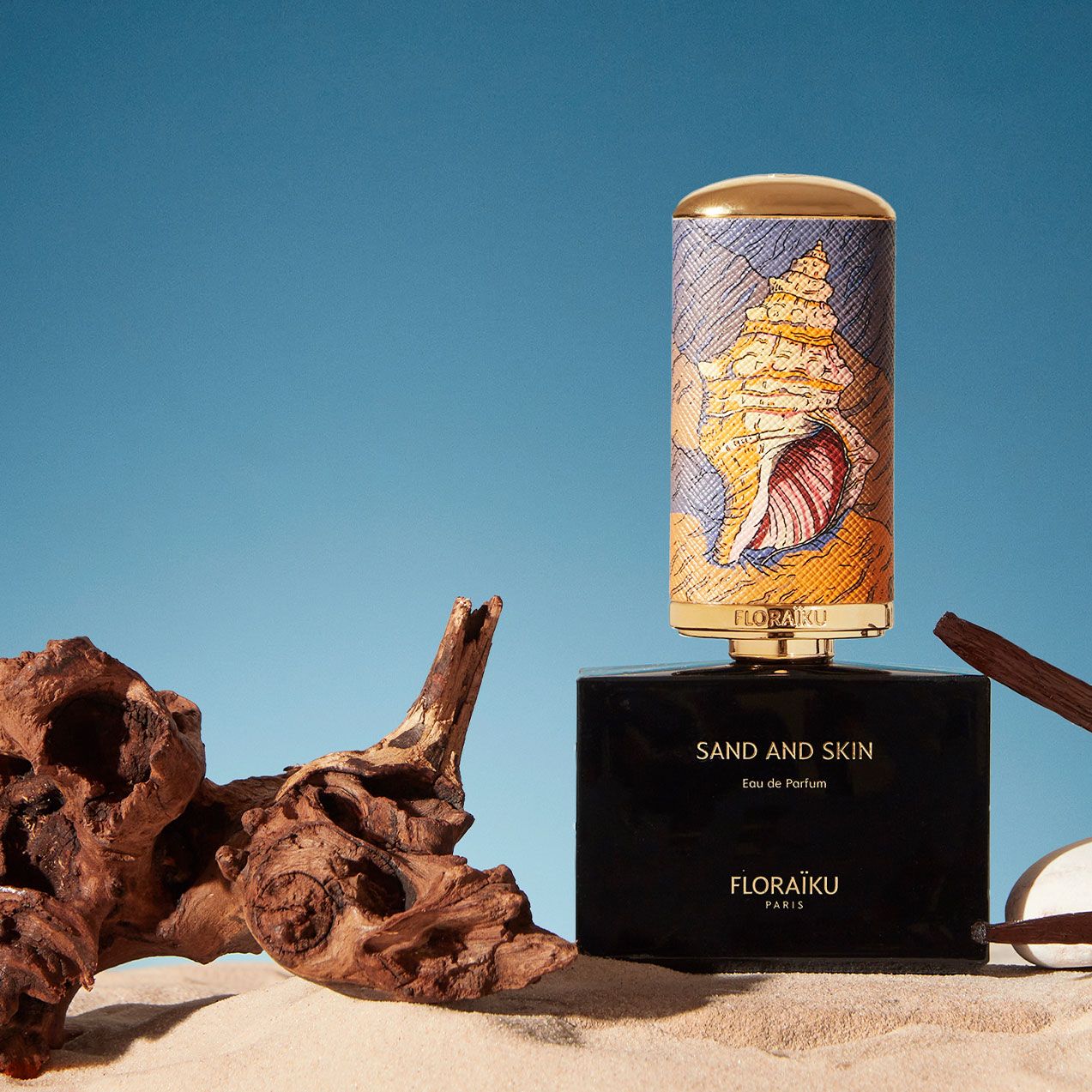 parfymen sand and skin från floraiku står bredvid en stock på sand