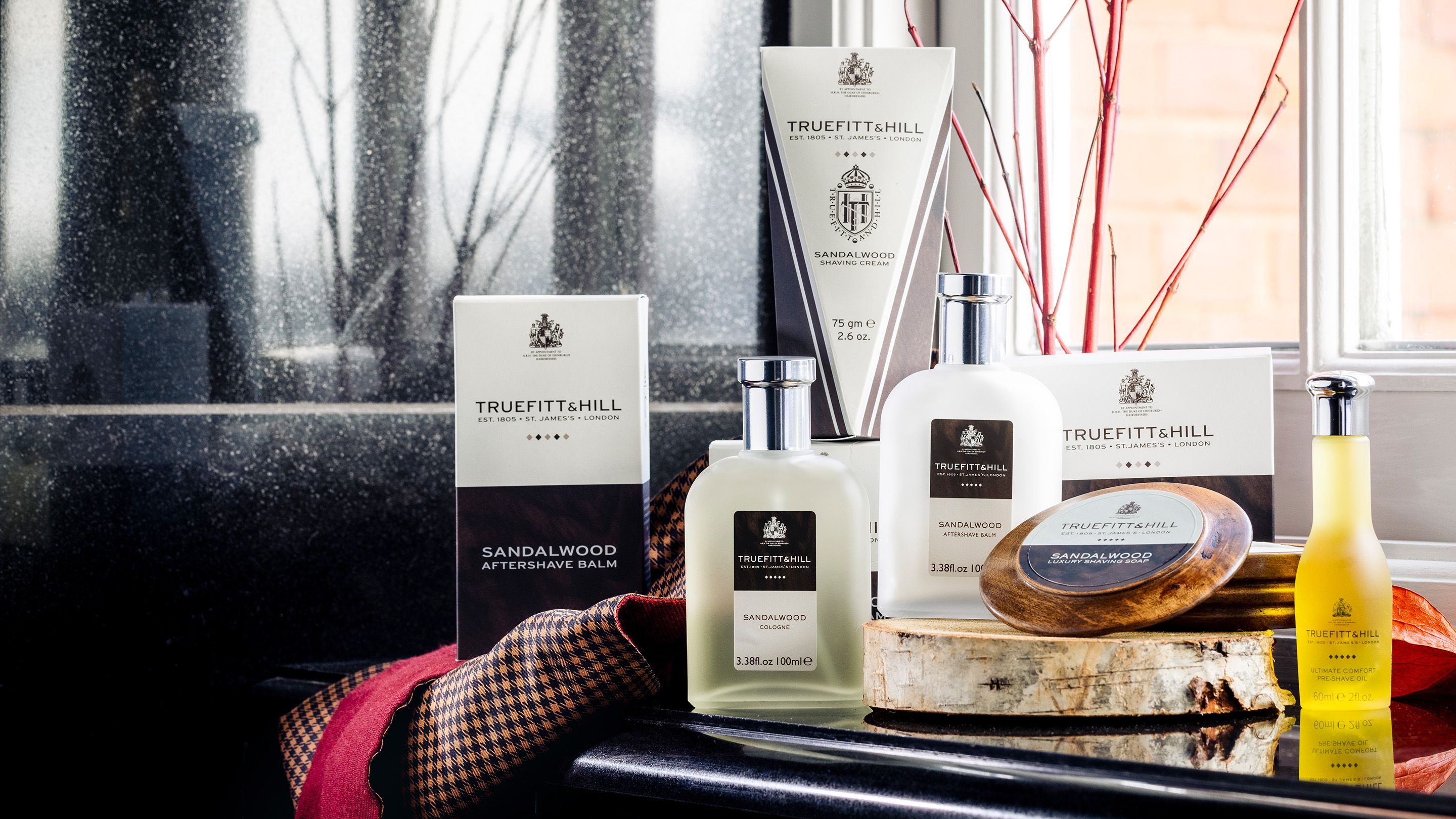 Truefitt & Hill Sandalwood-rakprodukter, inklusive aftershave, balm, rakkräm och tvål, på en disk.