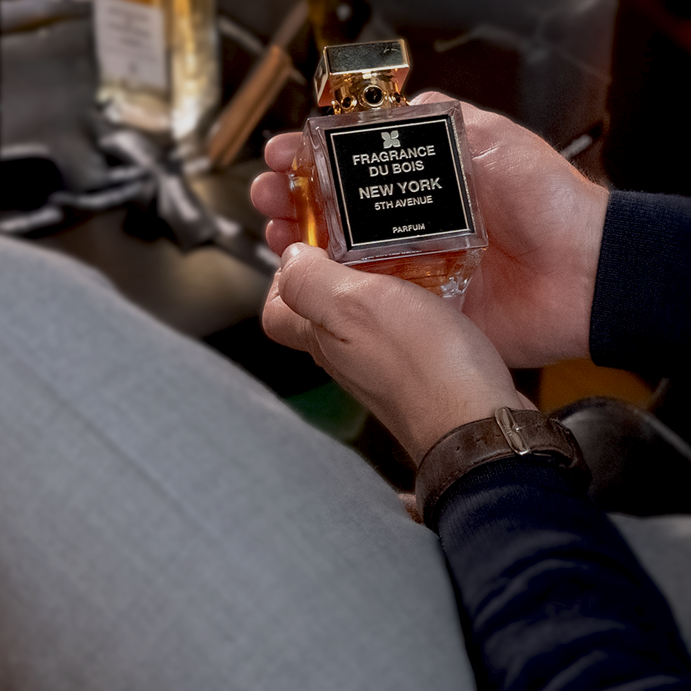 En man håller en parfym från Fragrance du Bois med båda händerna