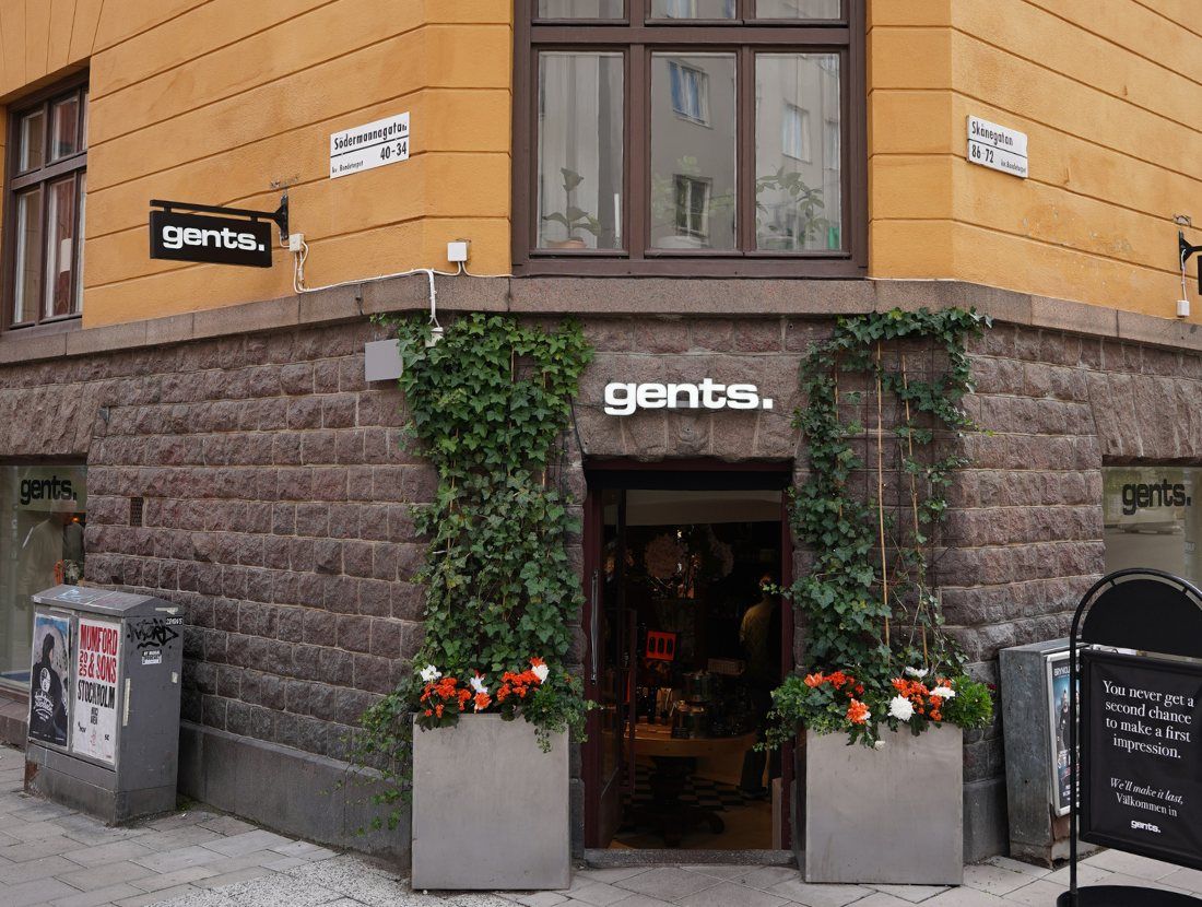 En parfymbutik med en mörkgrön upplyst disk, hyllor fyllda med parfymflaskor och en beige knäppt läderfåtölj.