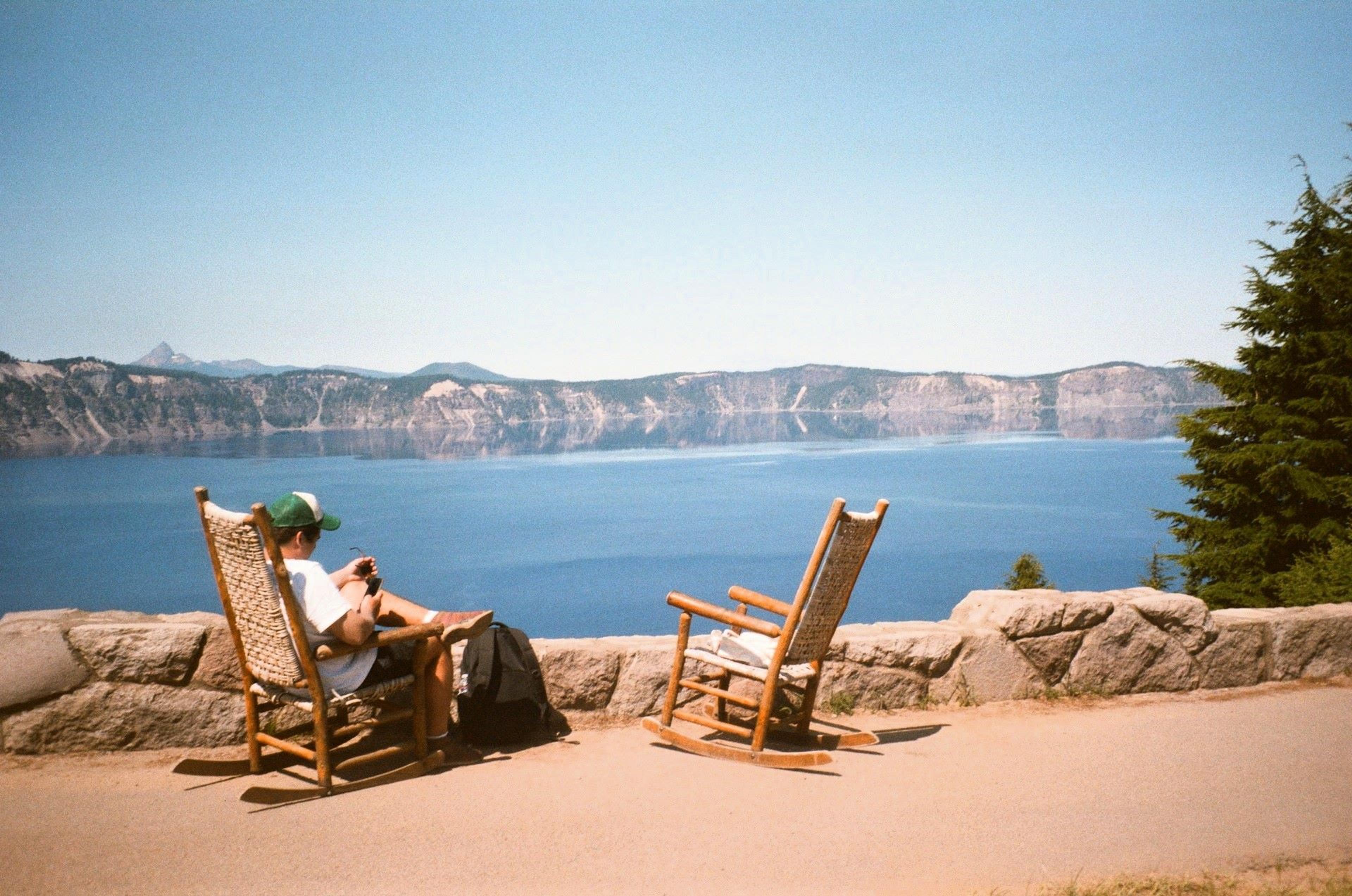 A person sitting on brown wooden rocking chair near Crater Lake, Oregon, USA