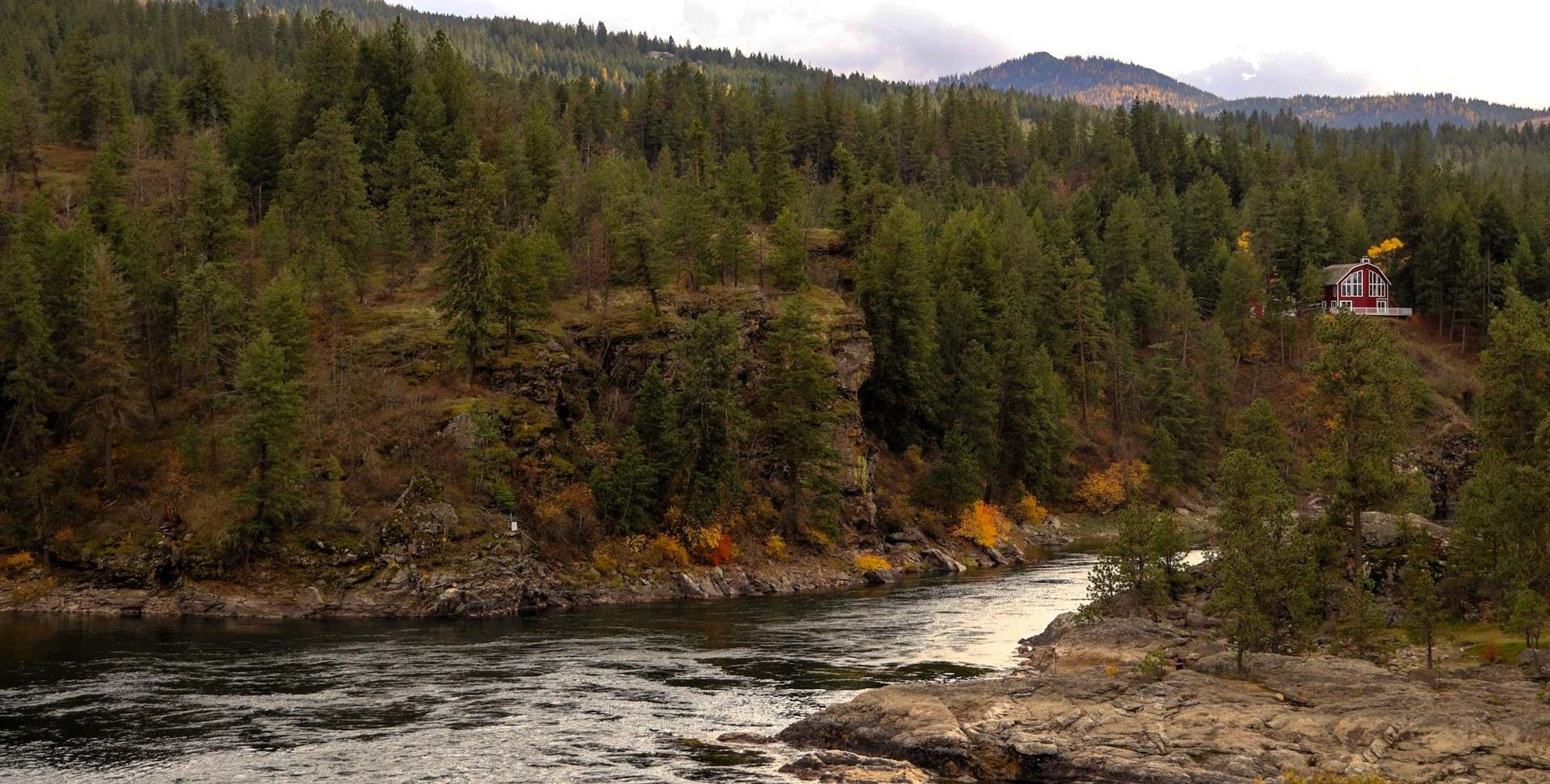 Spokane River, with a little red home on a hillside in Corbin Park near Post Falls, Idaho, USA