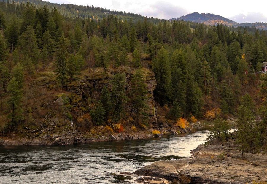 Spokane River, with a little red home on a hillside in Corbin Park near Post Falls, Idaho, USA