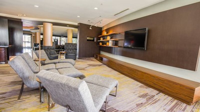 Photo of Courtyard Merced - lobby with a comfortable seating area, flat-screen TV, and shelves