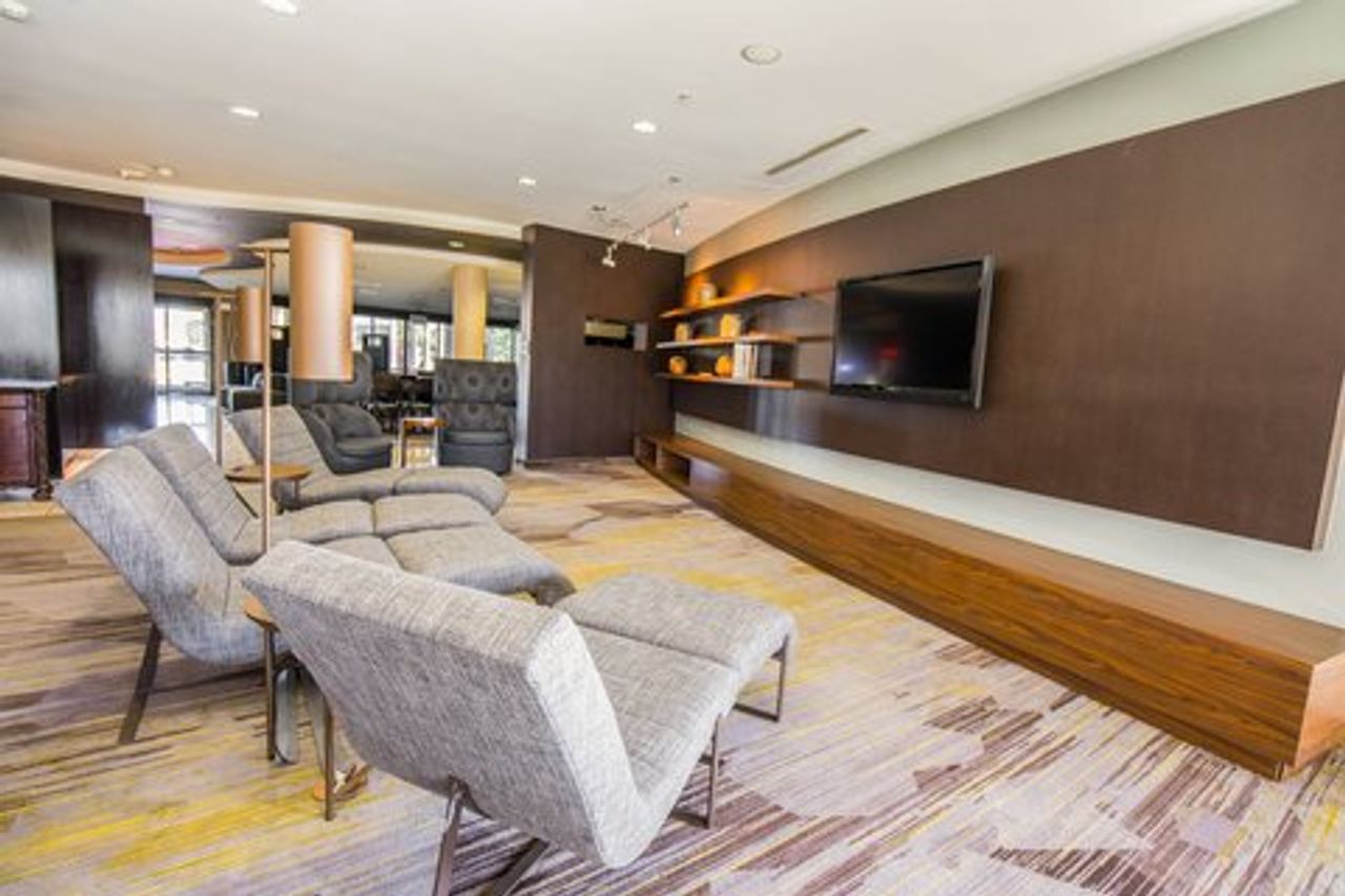 Photo of Courtyard Merced - lobby with a comfortable seating area, flat-screen TV, and shelves