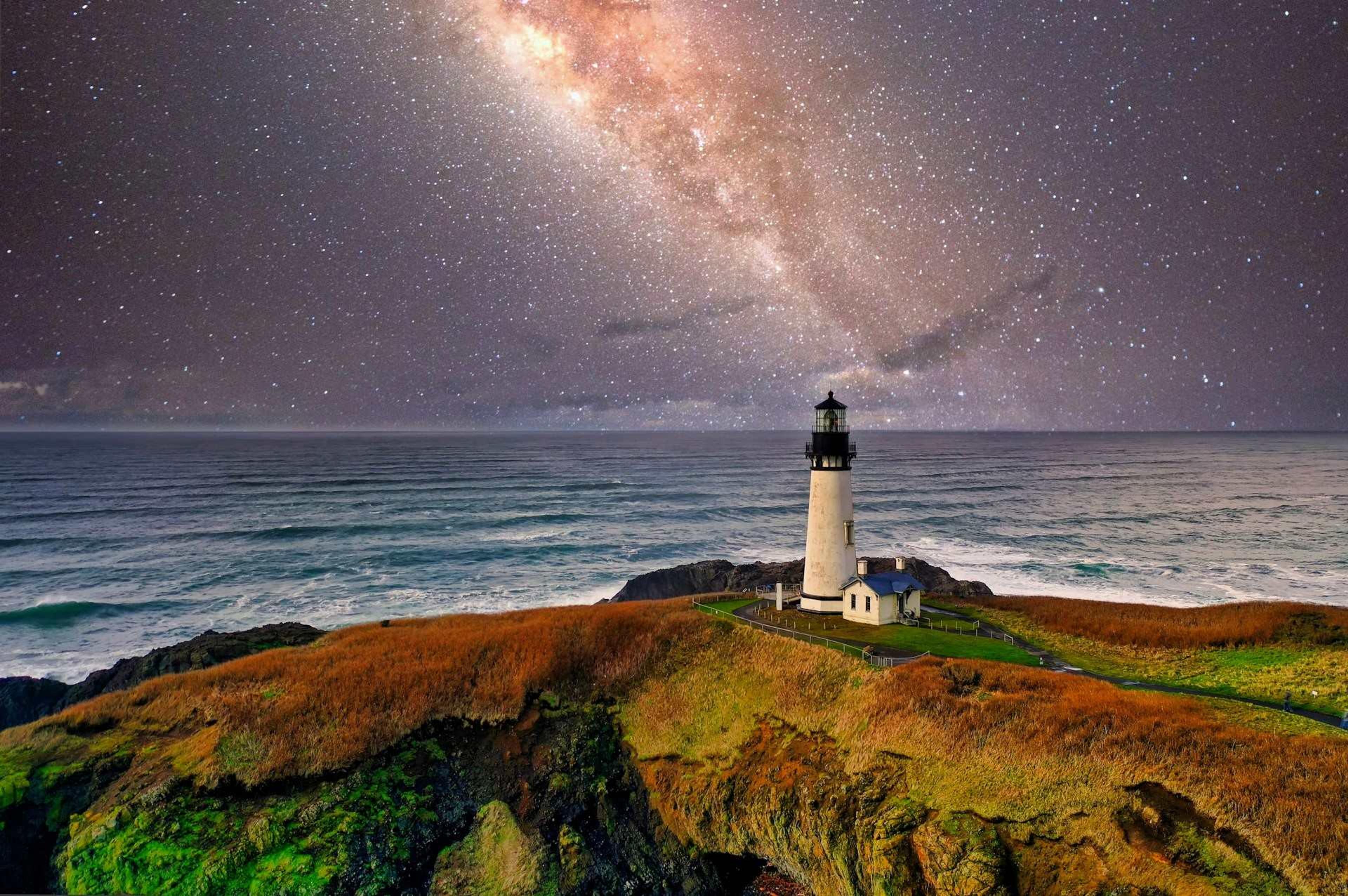 A lighthouse beneath a starry sky in Newport, Oregon.