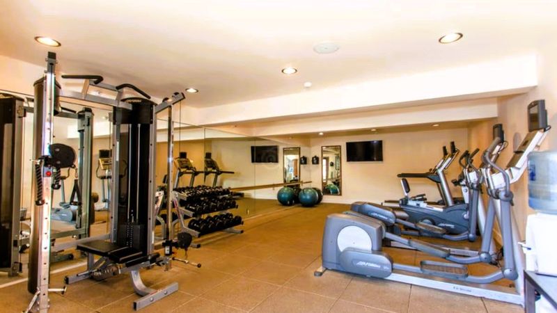 Photo of Casa Munras Garden Hotel & Spa - Fitness room with a Peloton bike, treadmill, elliptical, free weights, yoga mats, and Pilates balls