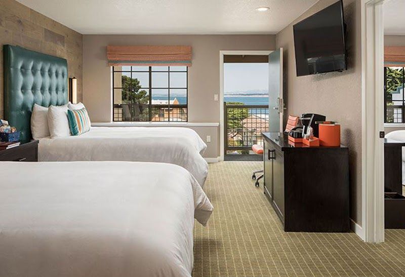 Photo of Wave Street Inn - The Wave Suite with two plush queen beds in one bedroom and a sitting area with chairs and a sofa sleeper in the family room