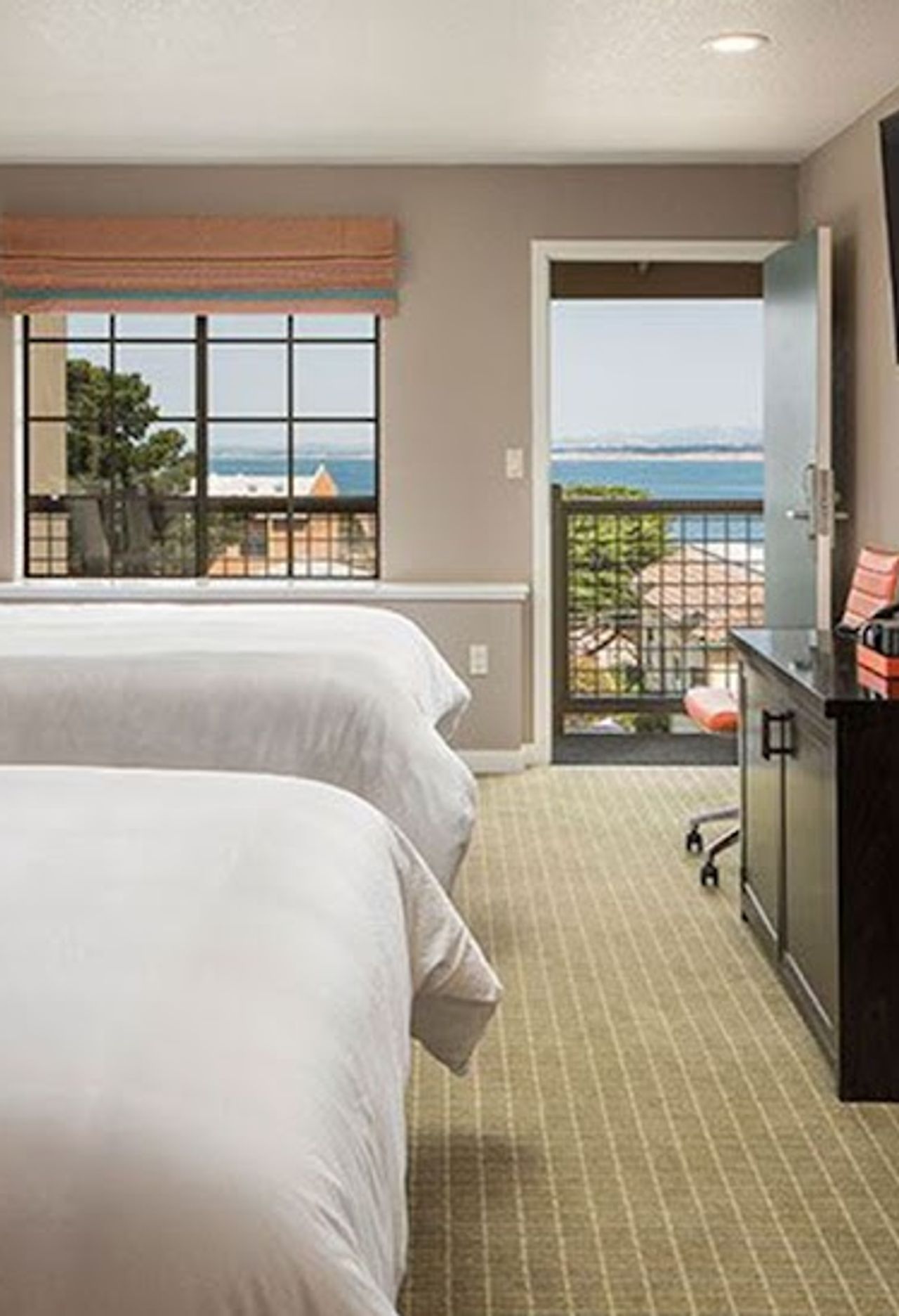 Photo of Wave Street Inn - The Wave Suite with two plush queen beds in one bedroom and a sitting area with chairs and a sofa sleeper in the family room