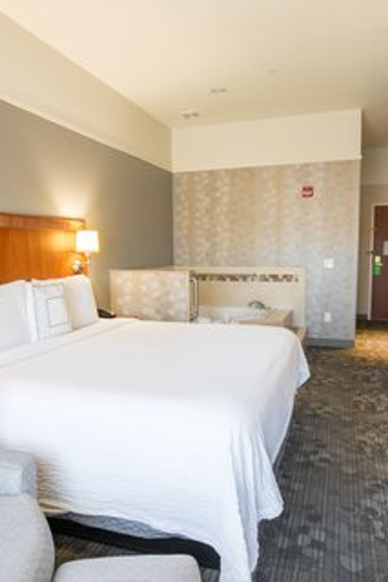 Photo of Courtyard Merced - A spacious room featuring a large bed, a private whirlpool tub, a sitting area with a chair and table, and a bathroom with a bathtub and shower.