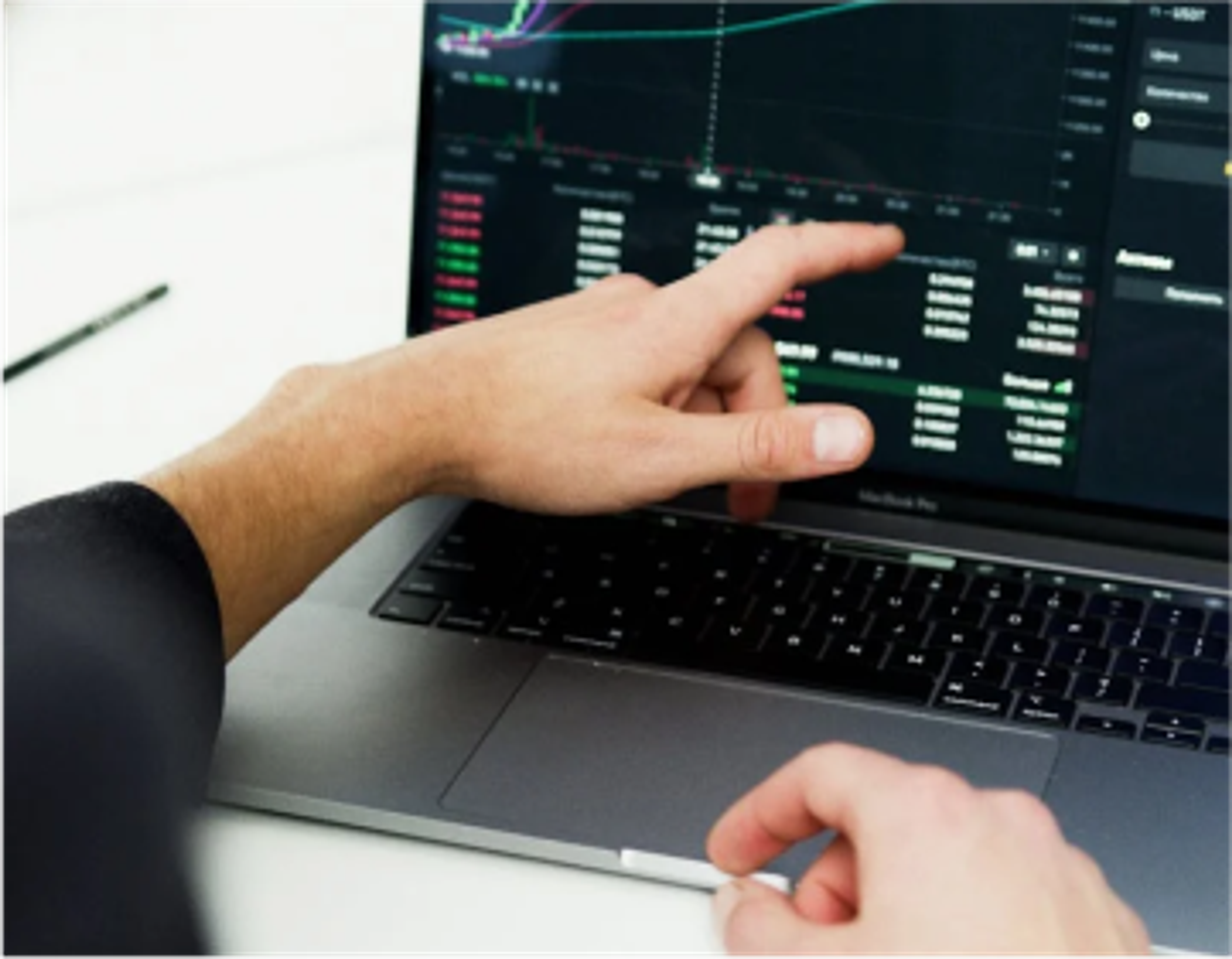 a person is pointing at a graph on a laptop