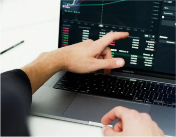 a person is pointing at a graph on a laptop