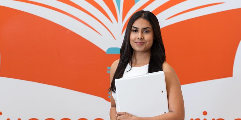 a woman is holding a white folder in front of a book .