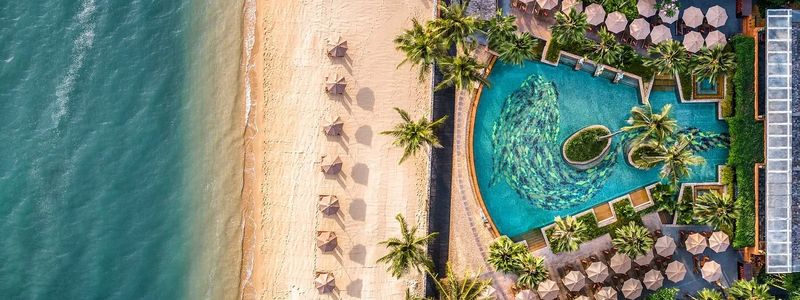 Beautiful long white beach with a tropical resort. Palm trees and sunbeds.