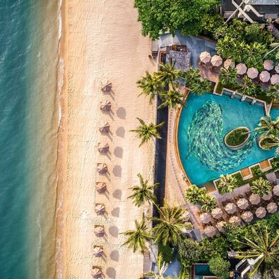 Beautiful long white beach with a tropical resort. Palm trees and sunbeds.