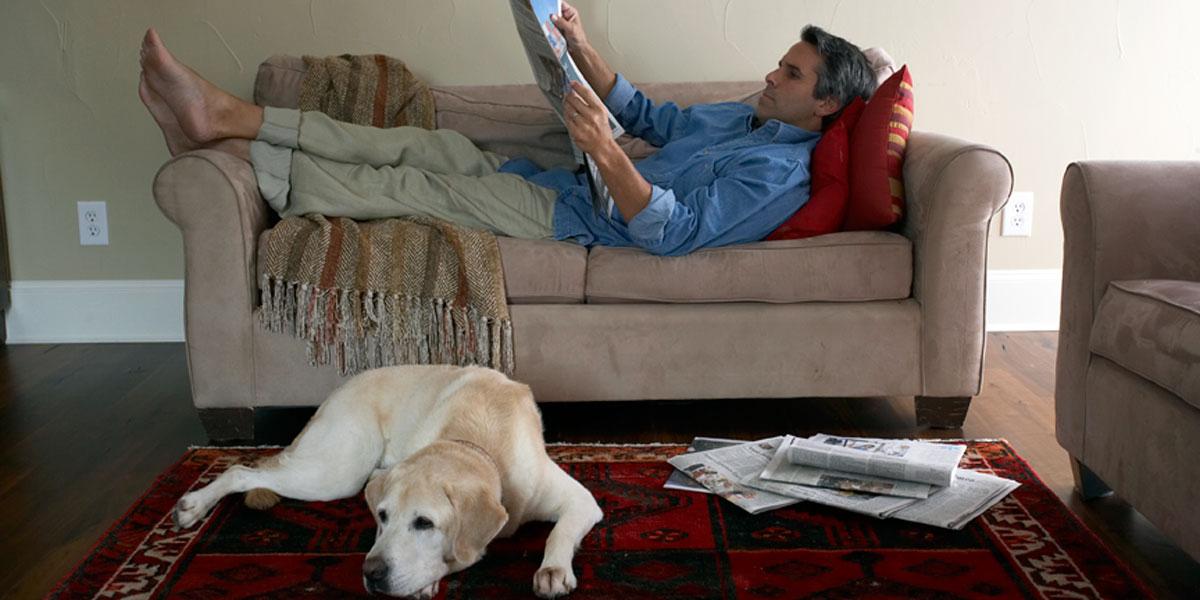 Man relaxing in a SS&B Heating & Cooling serviced home with his dog, enjoying the comfort of clean indoor air.