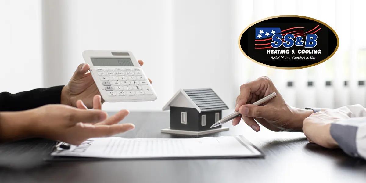 Two individuals discussing HVAC options with a model house, calculator, and documents on a table, featuring the SS&B Heating & Cooling logo.