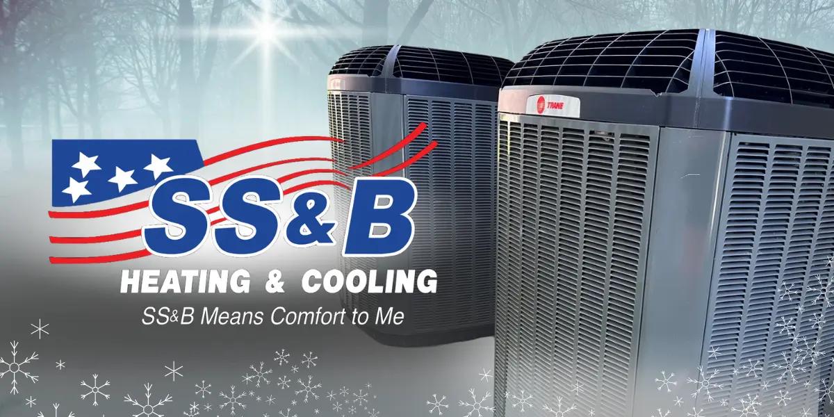 SS&B Heating & Cooling logo with two Trane outdoor heat pump units in a frosty, winter forest background. Snowflake graphics highlight the winter theme. SS&B Means Comfort to Me slogan featured.