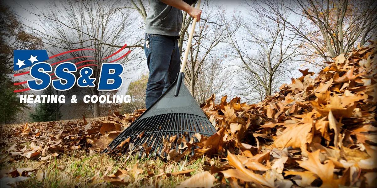 Person raking autumn leaves in a yard with the SS&B Heating & Cooling logo overlay, representing fall home maintenance and HVAC preparation.